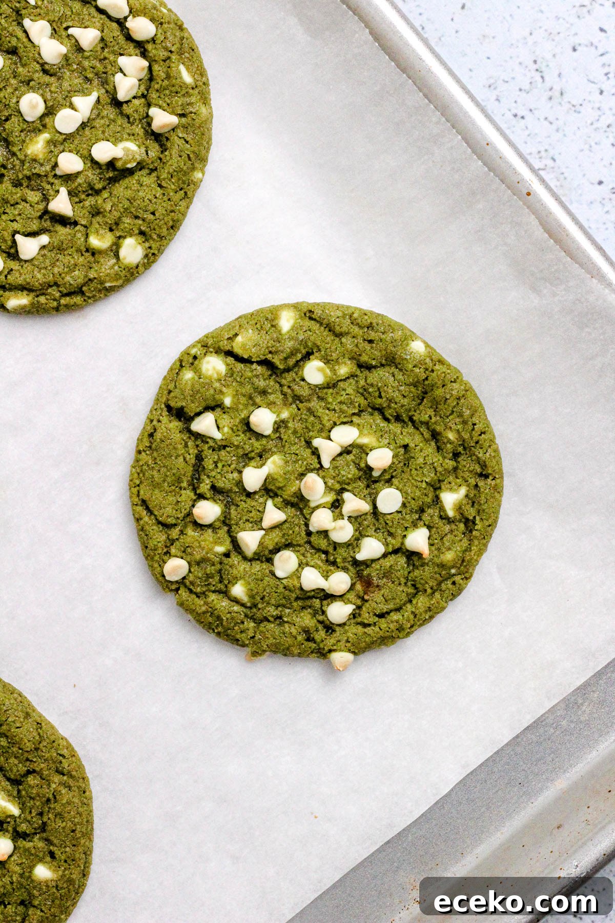 Matcha cookies with white chocolate chips on a parchment lined baking sheet.