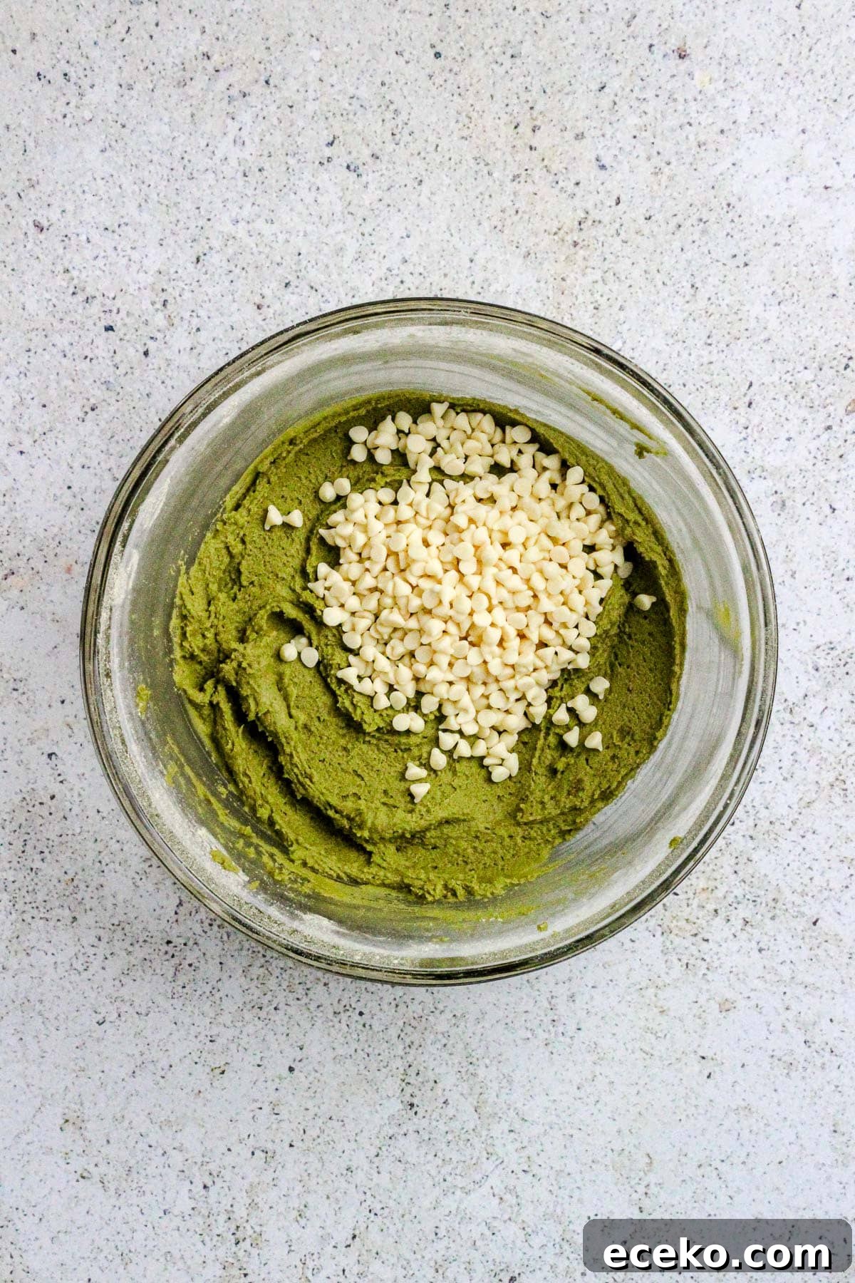 Matcha white chocolate chip cookie dough in a glass bowl.