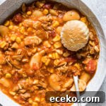 close up view of brunswick stew served in a blue bowl with a silver spoon