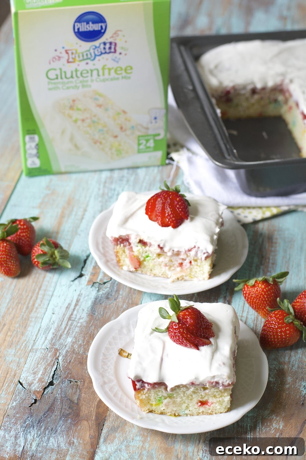 two slices of strawberry poke cake on white plates with box of cake mix in the background