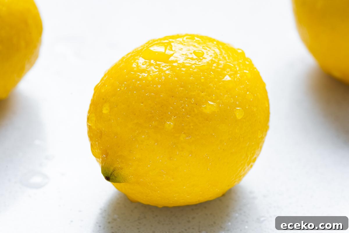 A close-up of washed lemon with water drops on a stone surface.