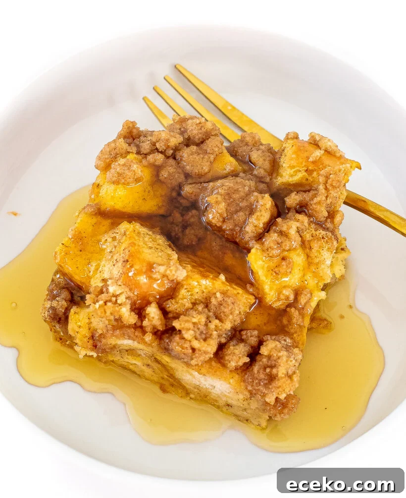 A slice of eggnog casserole topped with maple syrup on a white plate.