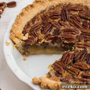 Golden crusted pecan pie with creamy filling and a slice missing, in a white pie plate.