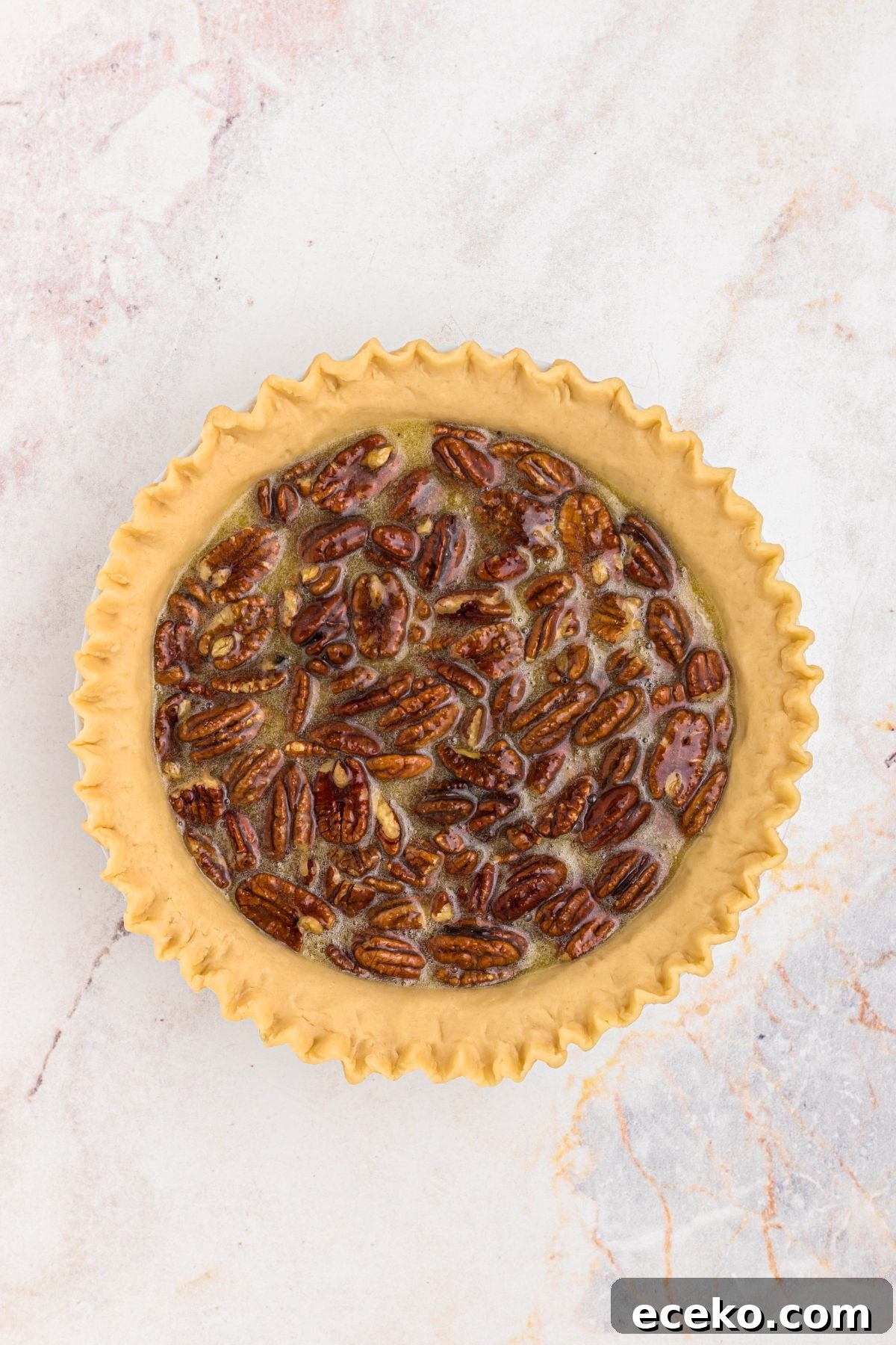 Pecans, eggs, and corn syrup, mixed together with sugar and other ingredients, then poured into an unbaked pie crust.
