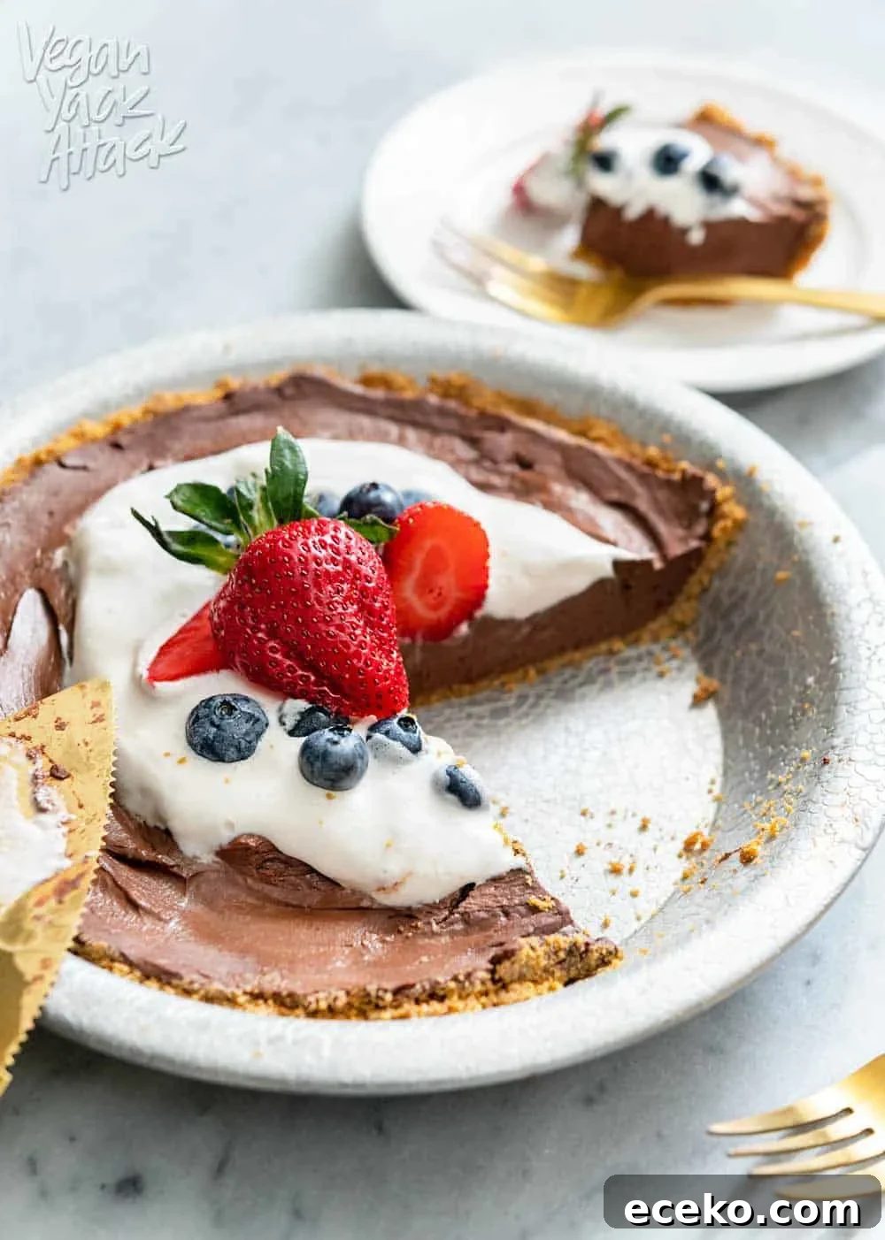 Slice of chocolate pie on a plate next to whole pie and gold pie server