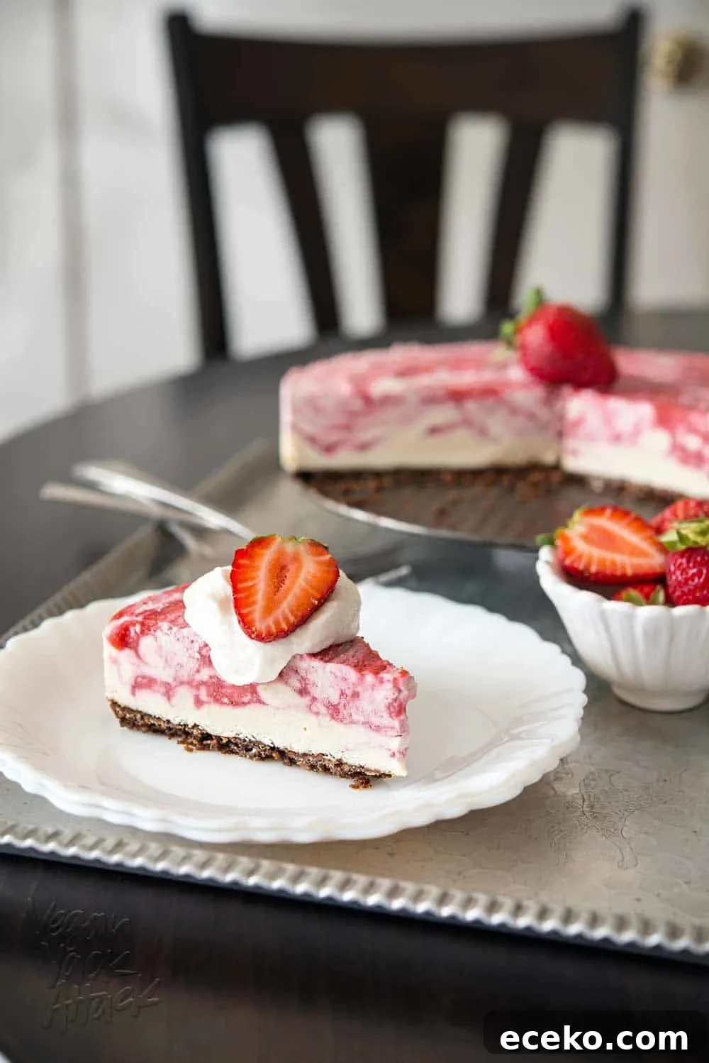 Slice of strawberry swirl cheesecake on a white plate