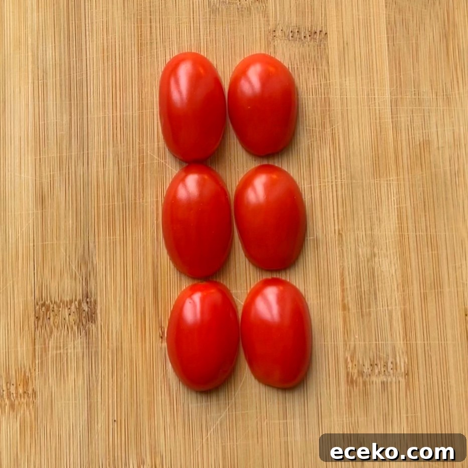 Festive Holiday Appetizers for Entertaining Guests 4 Six halved grape tomatoes are arranged in two vertical columns on a wooden cutting board.