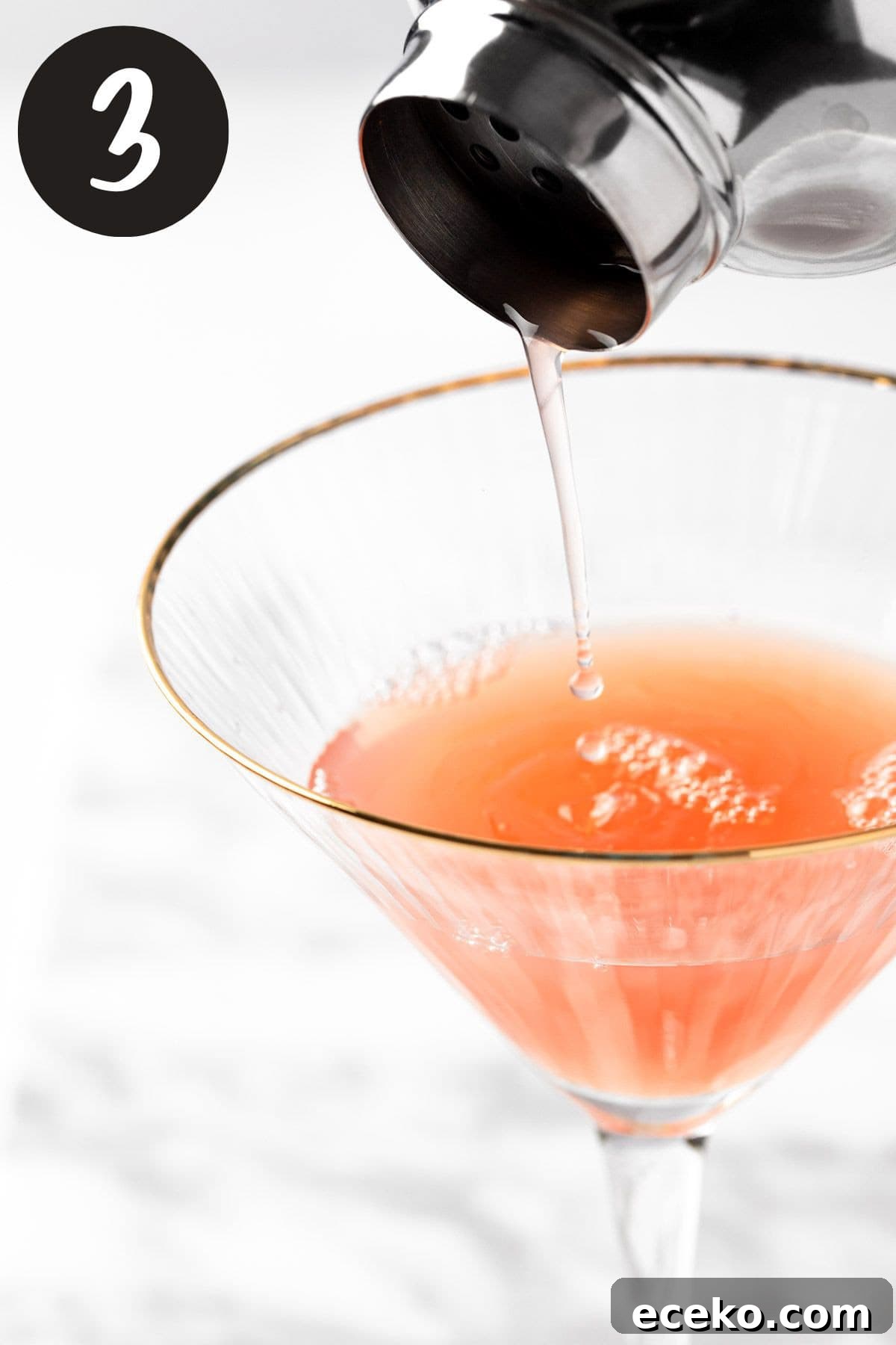 Pouring the martini from the cocktail shaker into a martini glass.