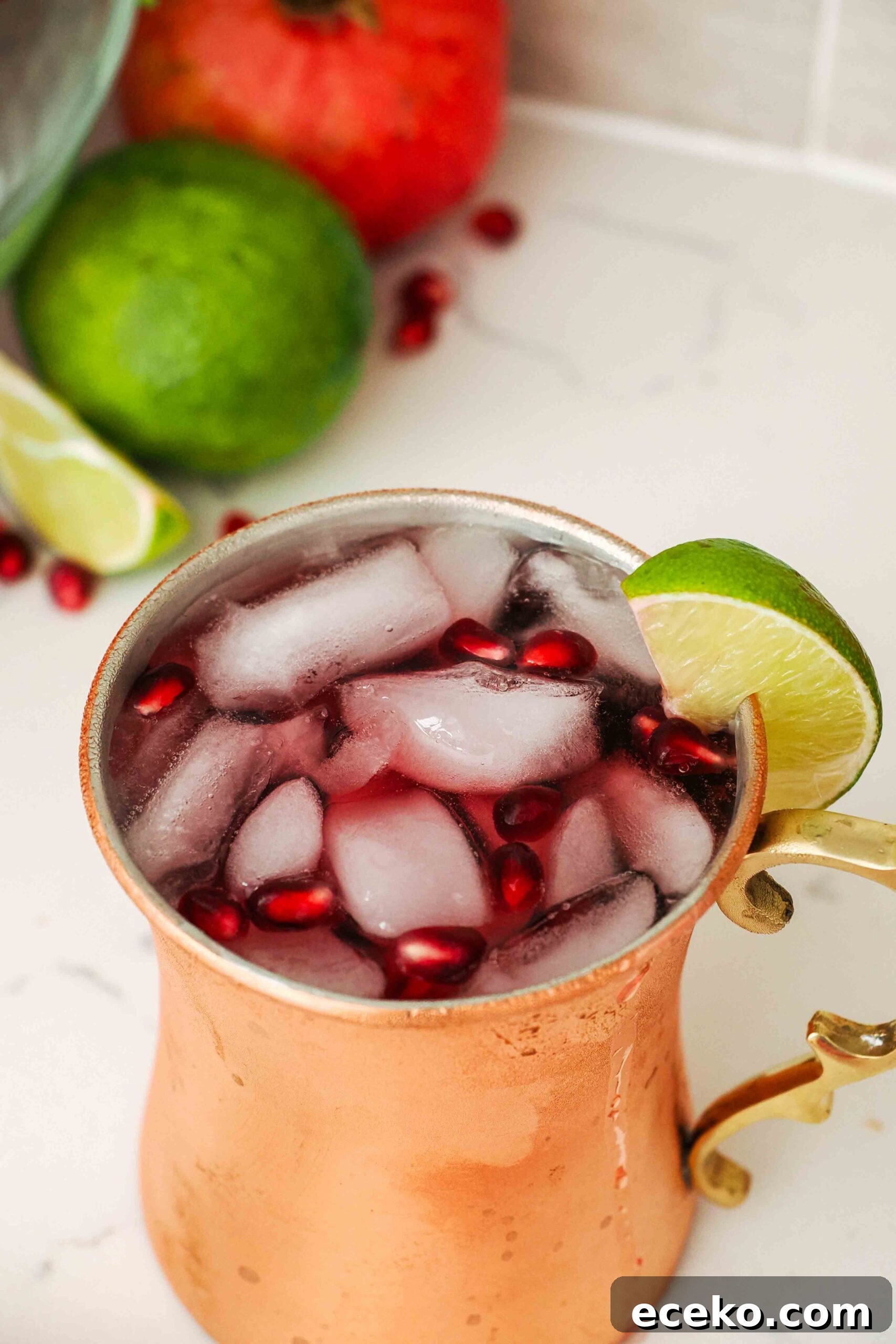 A closeup image of a pomegranate Moscow mule in a copper mug.