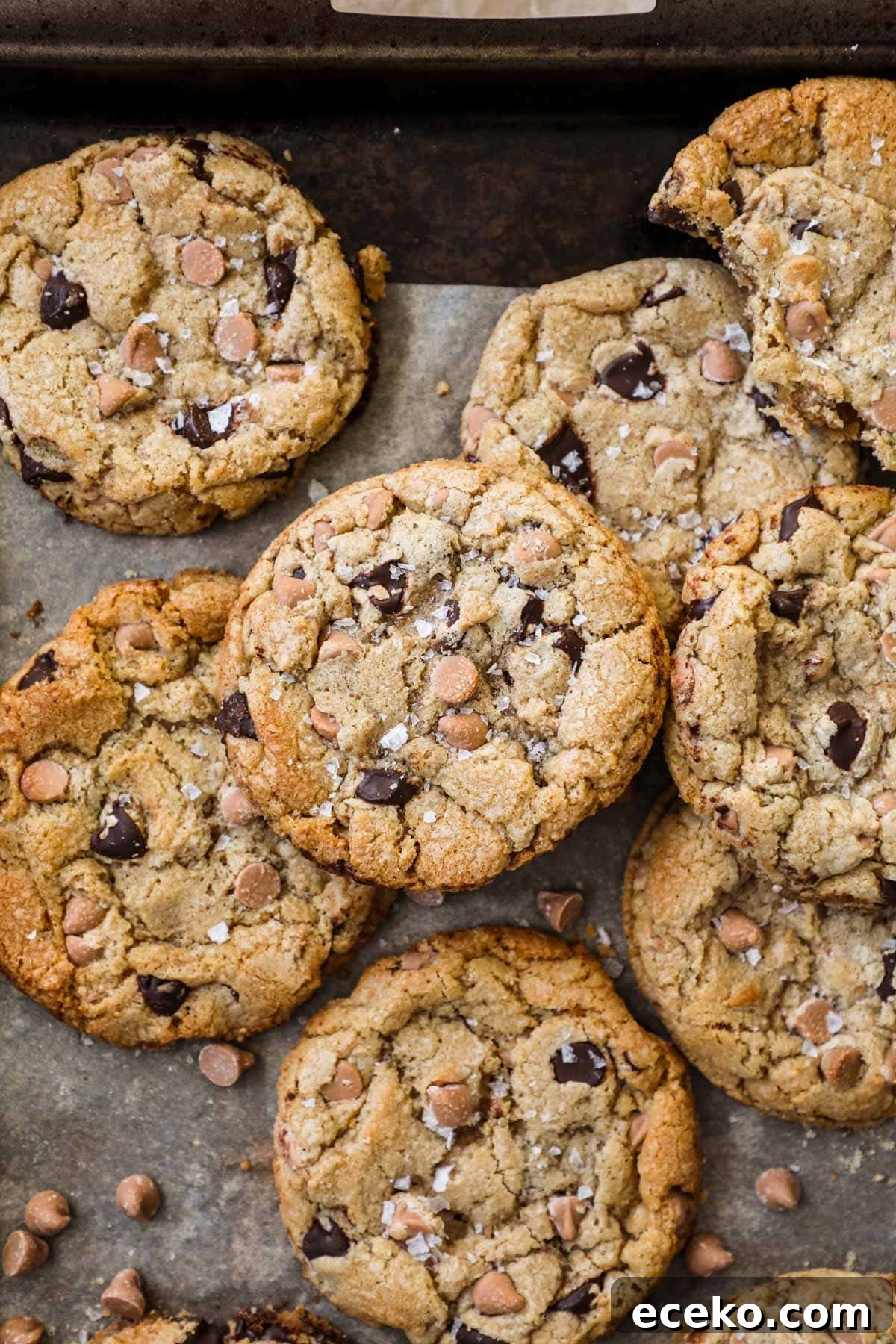 Butterscotch chocolate chip cookies with flaky sea salt on a baking sheet lined with parchment paper.