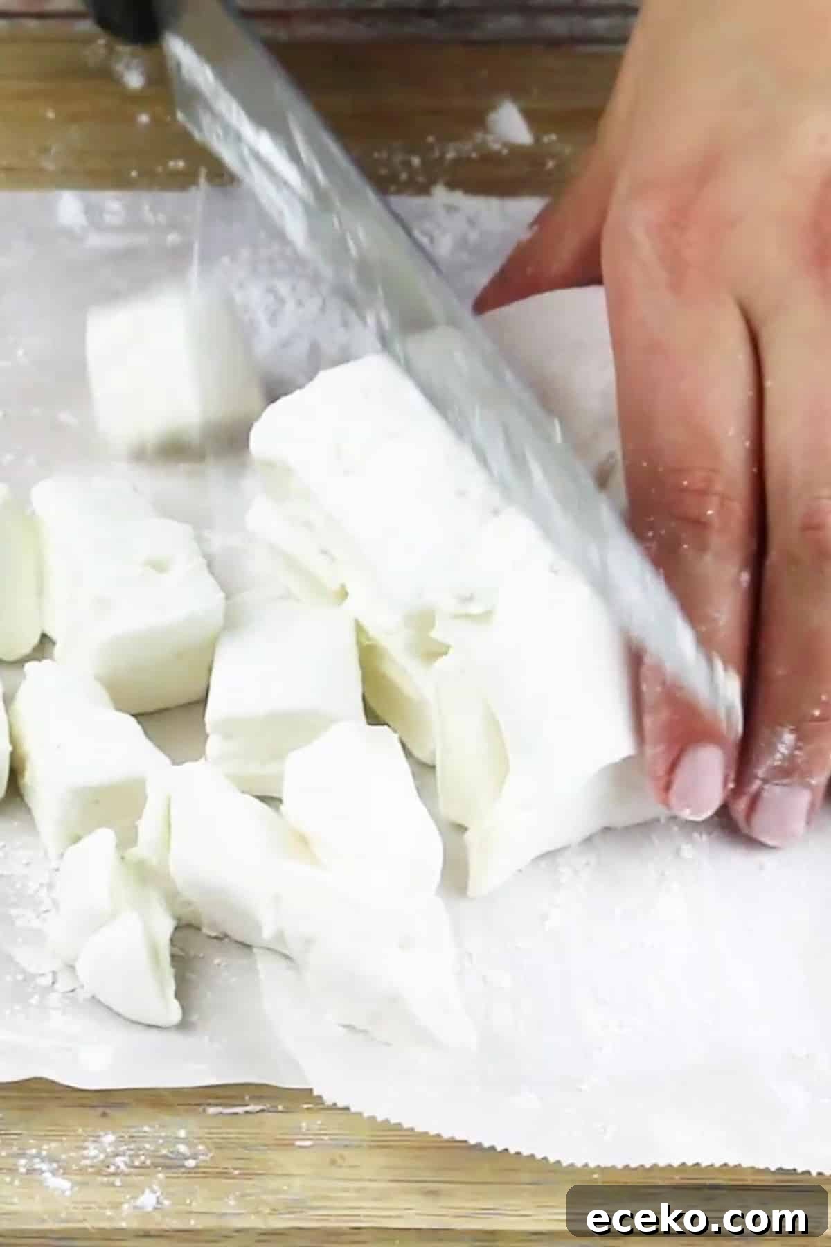 Homemade Marshmallows Without Corn Syrup — Simple Recipe 9 homemade marshmallows cut into small pieces with a chef's knife.