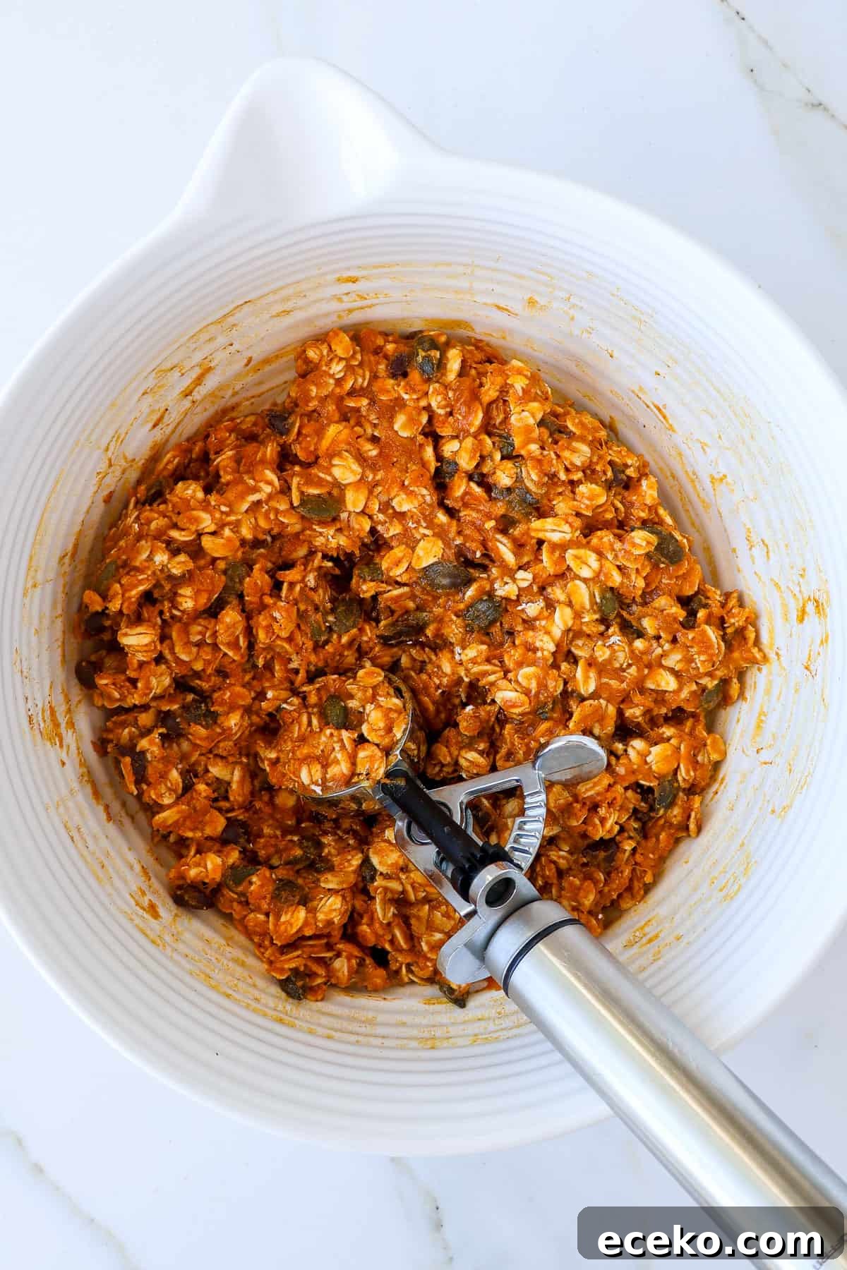 Protein ball mixture in a bowl with a cookie scoop