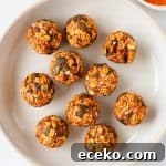 Pumpkin protein balls in a bowl with pumpkin puree and pumpkin seeds on the side. One ball has a bite.