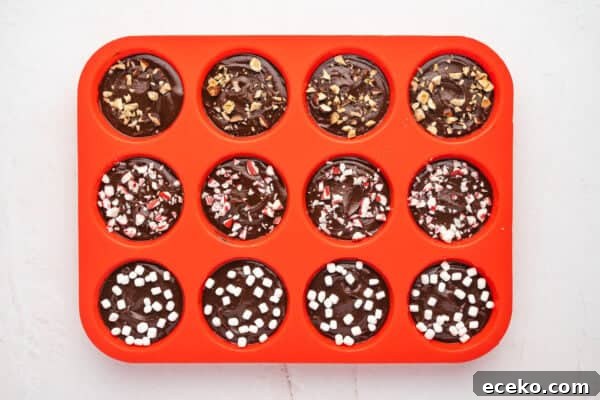 Hot Chocolate Sticks: Easy Melt-and-Serve Cocoa Treats 6 Melted chocolate in a silicone muffin tin topped with marshmallow bits, crushed nuts, and crushed peppermint