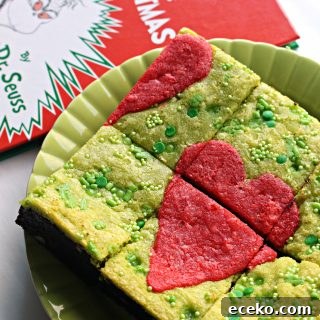 Green Grinch Brownies with a red heart on top on a green plate next to book.