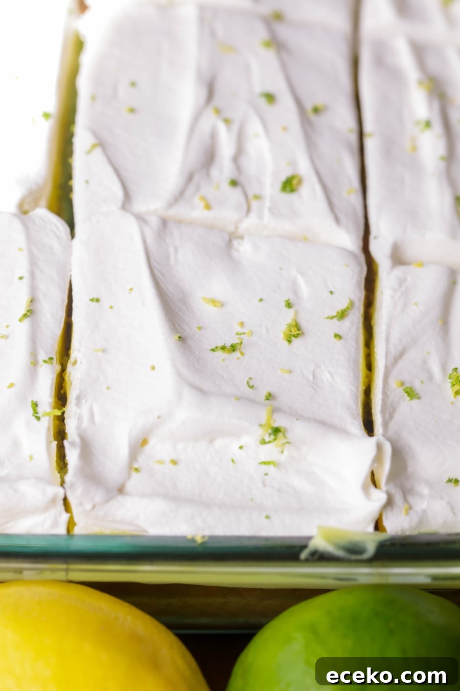 Lemon Lime Poke Cake is full of lime flavor, topped with creamy lemon pudding and topped with whipped cream and zest! Sliced whipped cream covered lemon lime poke cake