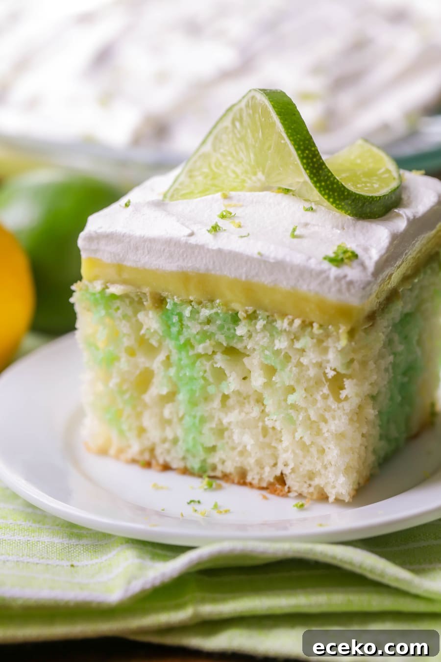 Lemon Lime Poke Cake is full of lime flavor, topped with creamy lemon pudding and topped with whipped cream and zest! Lime twist topped slice of lemon lime poke cake