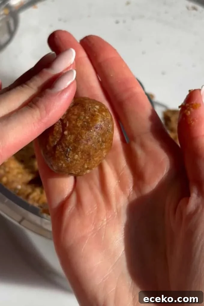 two hands rolling a carrot cake energy ball