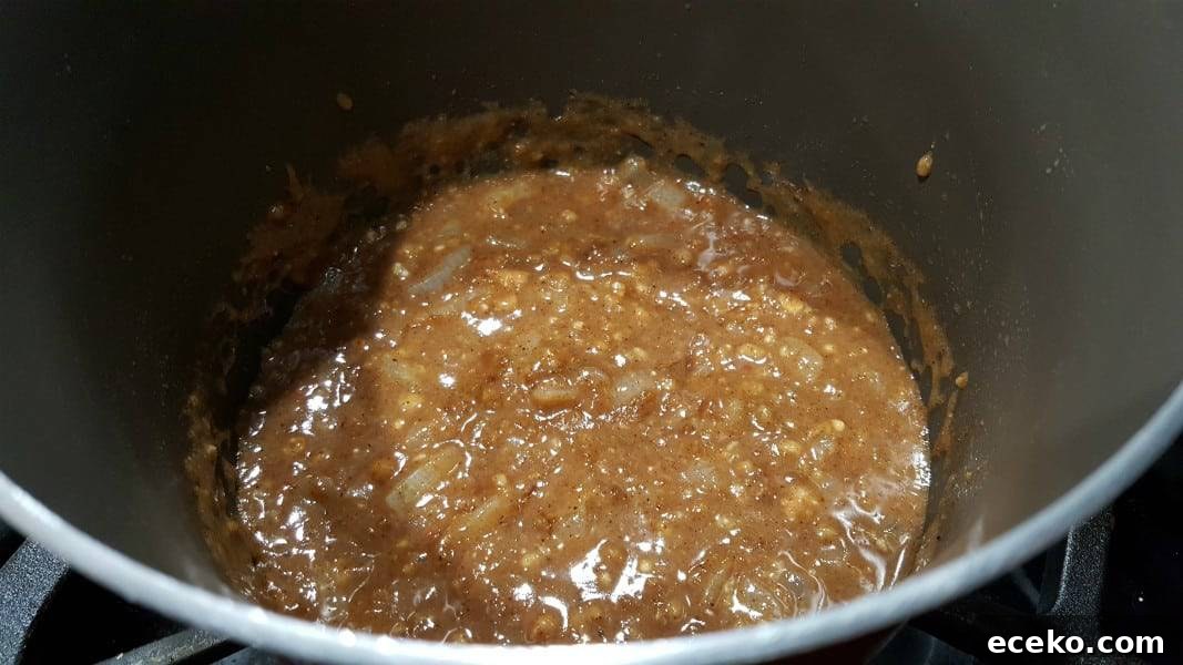 Creamy Shrimp Korma Recipe with Aromatic Spices 5 korma sauce ingredients mixed in with chopped onion cooking in a pan.