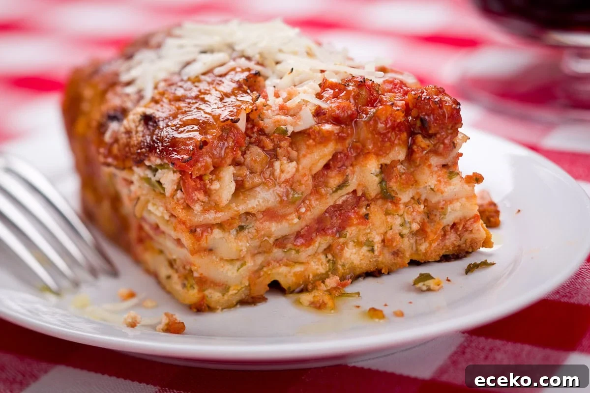 A big slice of lasagna with layers of cheese and sauce on a white plate. 