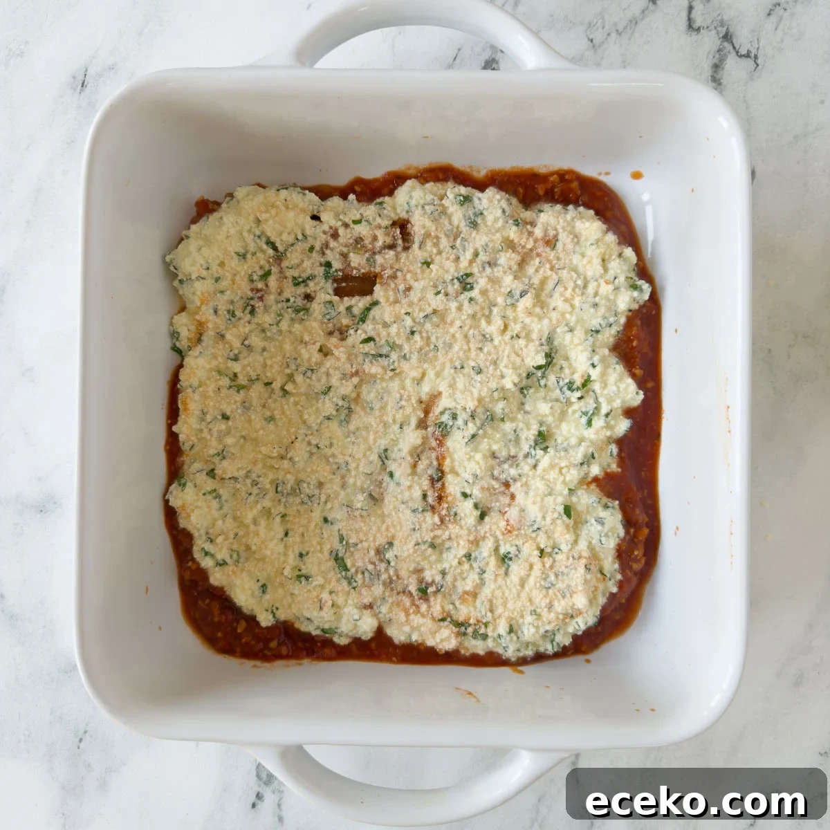 More layering for making gluten-free lasagna with noodles, ricotta, and sauce in a white casserole.