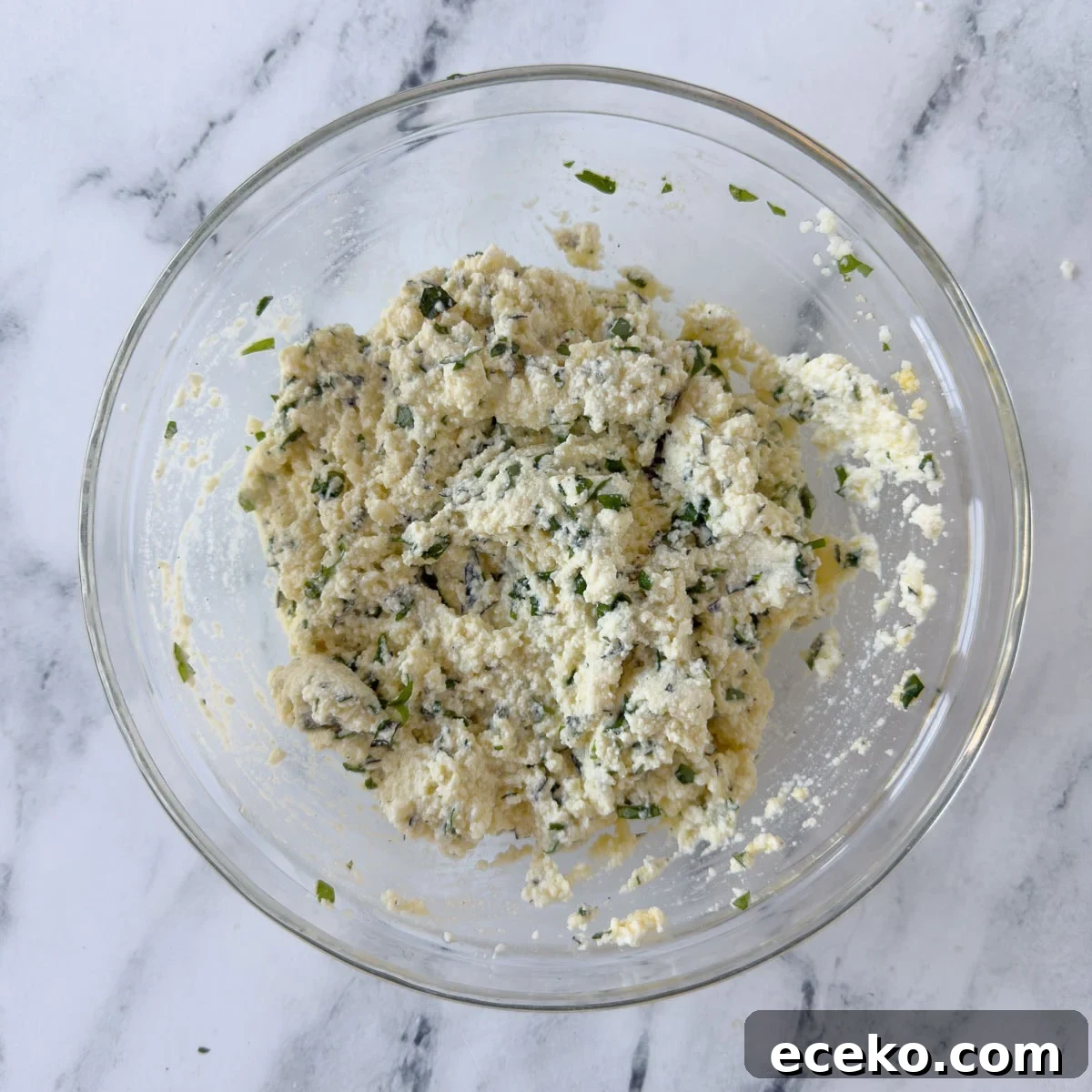 Ricotta cheese filling for lasagna in a glass bowl.