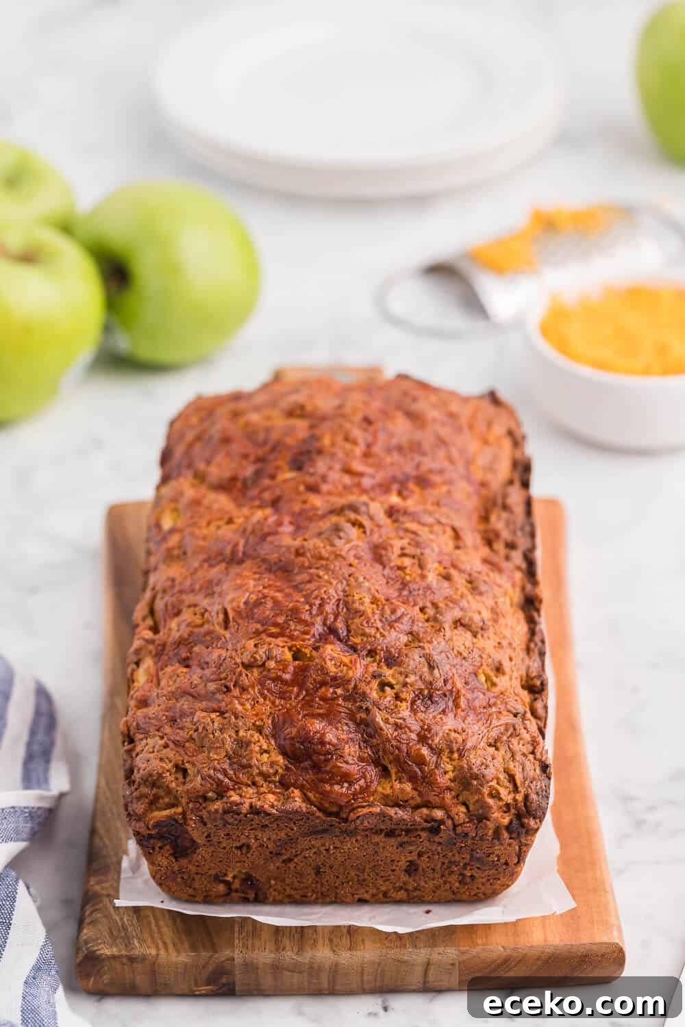 A loaf of apple cheddar bread on a cutting board