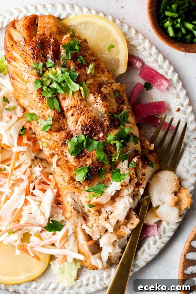 blackened cod on a plate with slaw and lemons