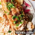 blackened cod on a plate with slaw and lemons
