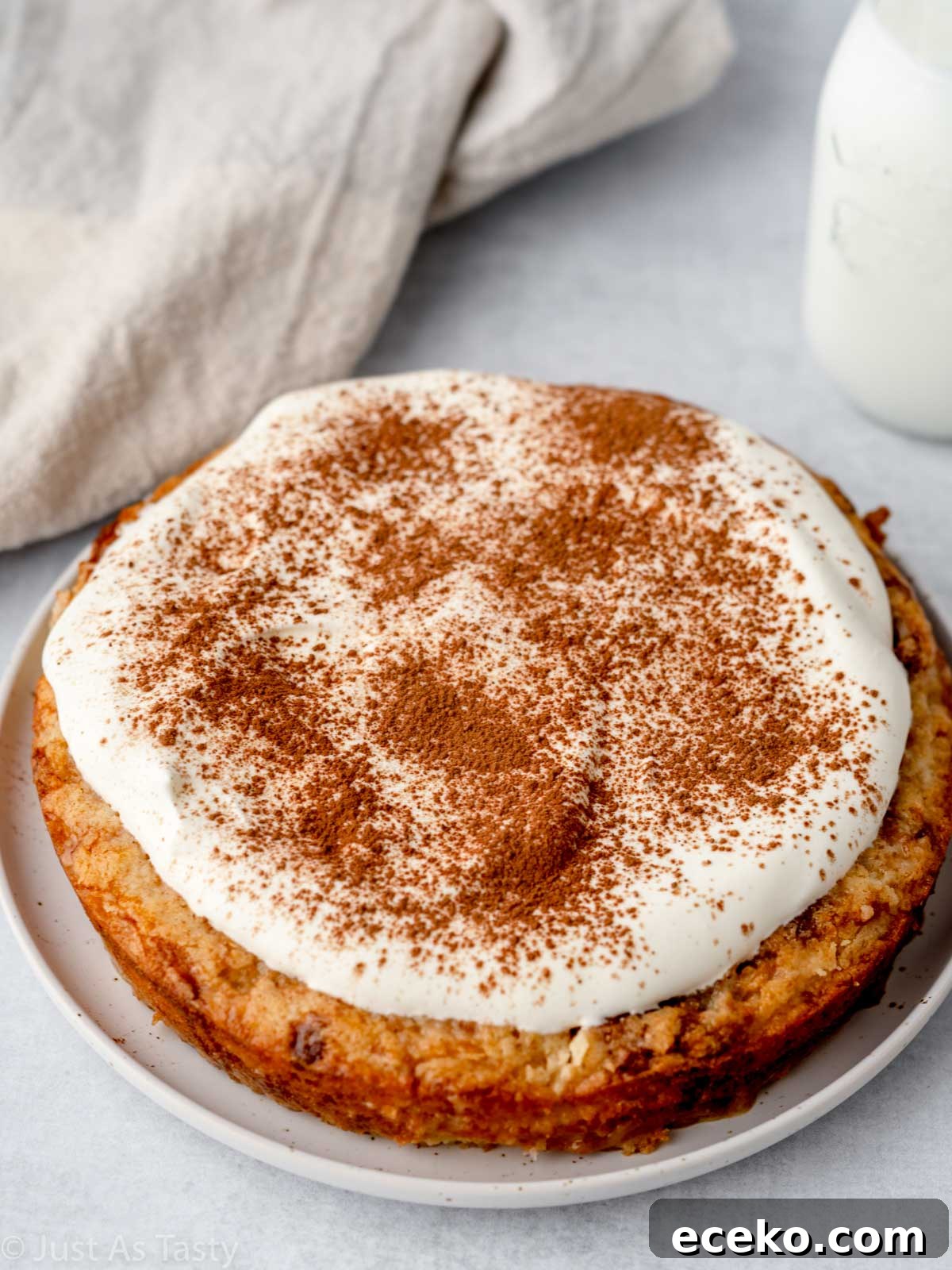 Gluten free tres leches cake topped with whipped cream on a white plate. 