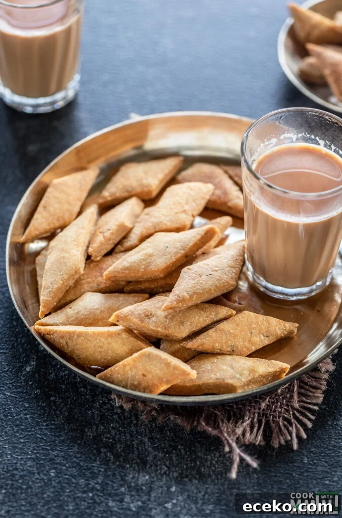 namak para served in a copper plate with glass of chai on the side