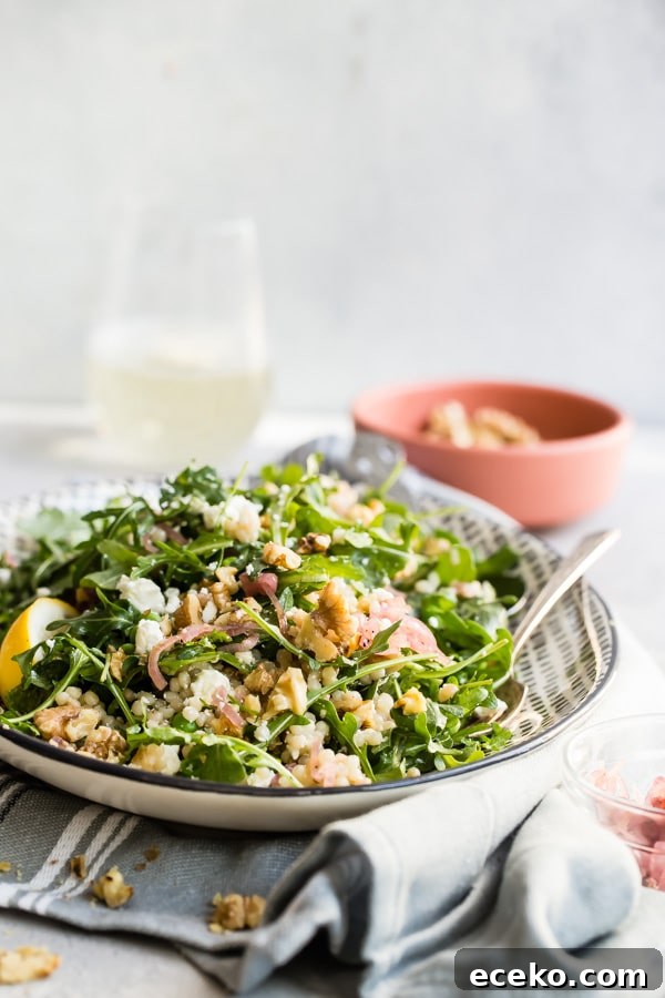 Israeli couscous salad with arugula and walnuts on a plate.