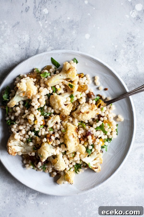 Israeli couscous salad with cauliflower and raisins on a plate.