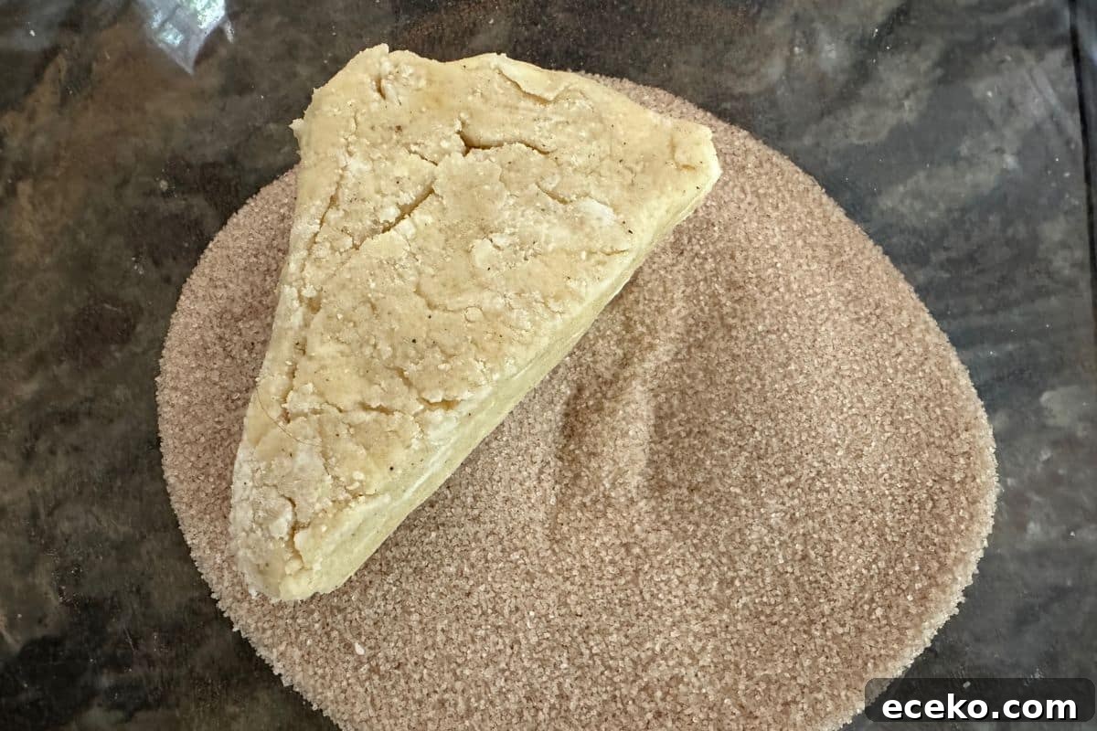 A scone wedge of dough in the cinnamon sugar mixture.