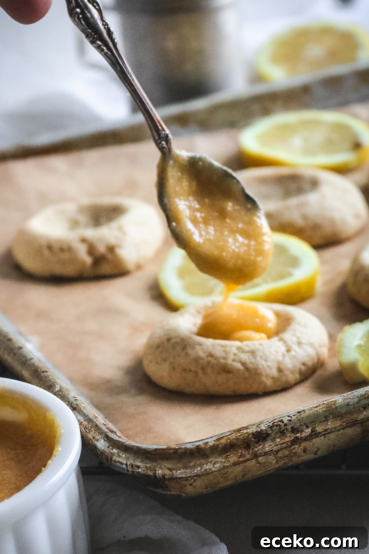 spooning lemon curd into freshly baked vanilla cookies to make lemon curd cookies.