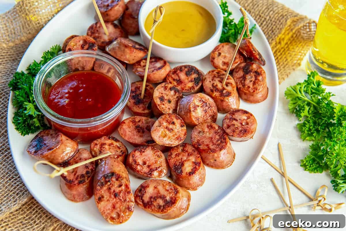Savory Chicken Sausage Bites for Party Appetizers 4 Platter of browned chicken sausage bites served with honey mustard and chili jam dipping sauces, garnished with parsley and toothpicks for easy serving.
