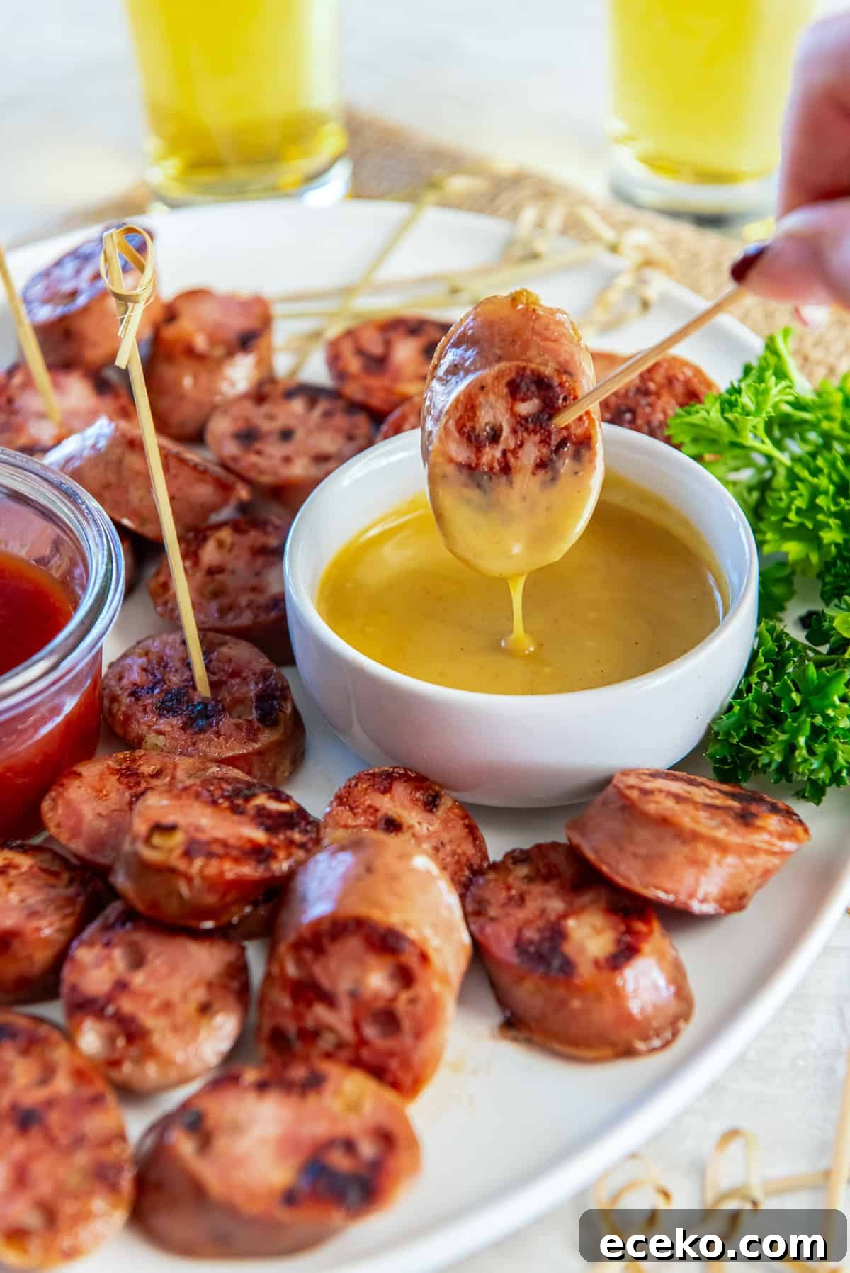 Savory Chicken Sausage Bites for Party Appetizers 8 Chicken sausage bite dipped into creamy honey mustard sauce, showing the thick texture of the dip on a white serving platter.