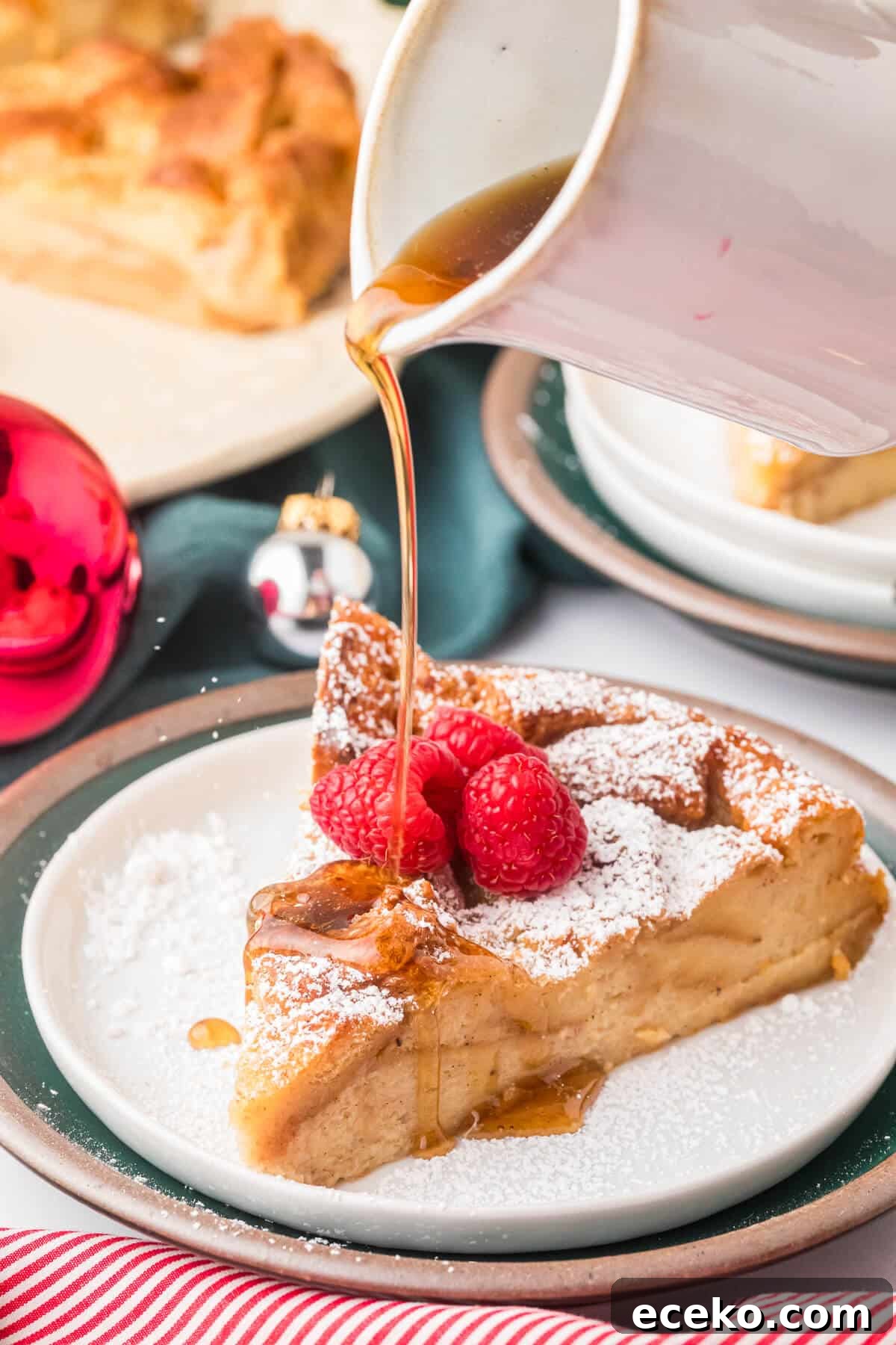 Eggnog Bread Pudding with Cinnamon-Caramel Sauce 6 A slice of eggnog bread pudding on a plate with syrup being poured on it.