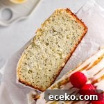 A slice of lemon poppy seed loaf cake with fresh raspberries and a simple glaze.