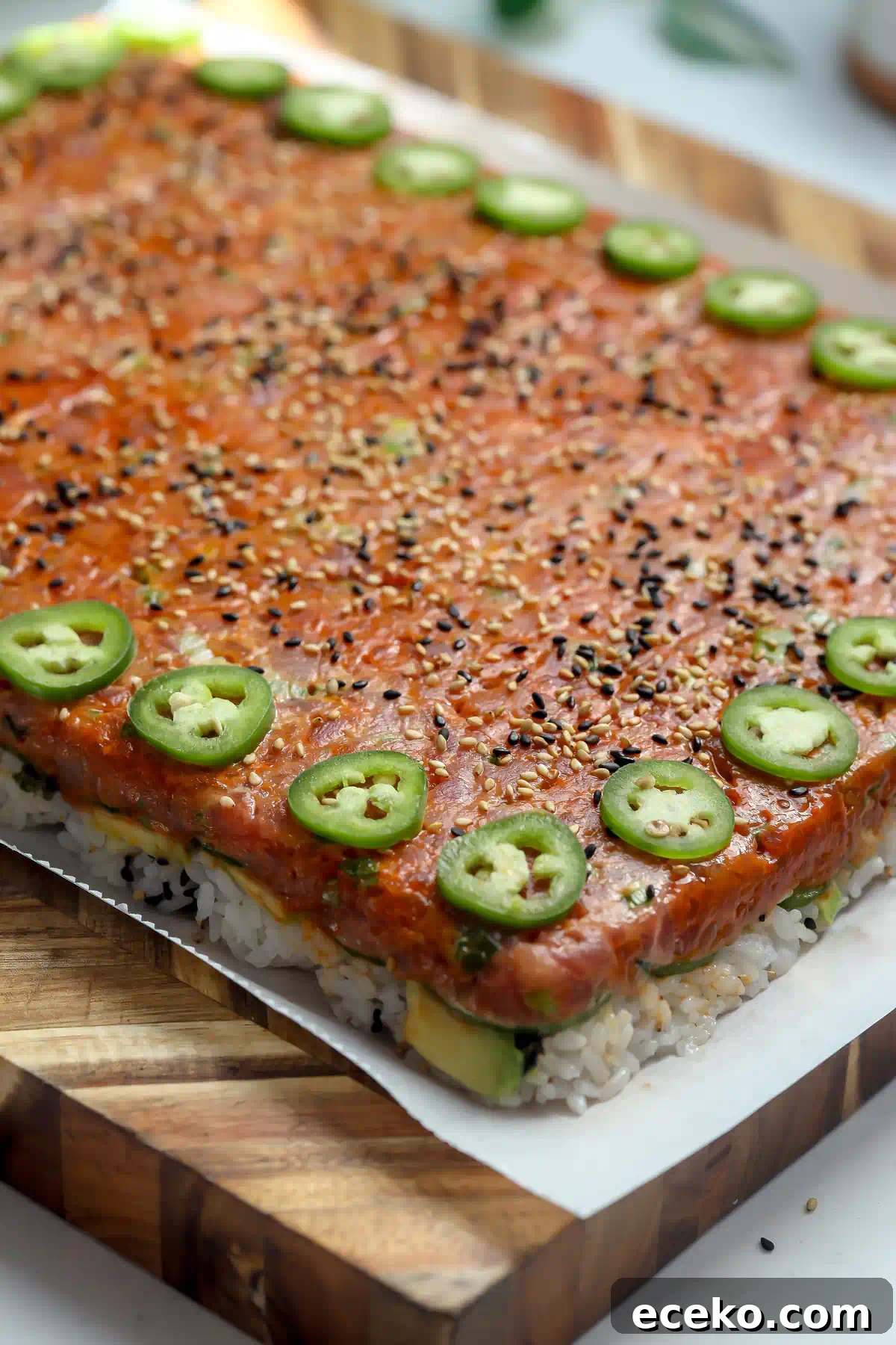 Spicy Tuna Oshizushi: Pressed Sushi Recipe 9 Side view of spicy tuna pressed sushi showing layers of seasoned rice, avocado, and cucumber under the gochujang tuna, oshizushi style.