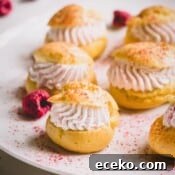Raspberry Crème Puffs with Vanilla Cream Filling 12 Mini raspberry cream puffs on a white platter dusted with freeze-dried raspberry powder.
