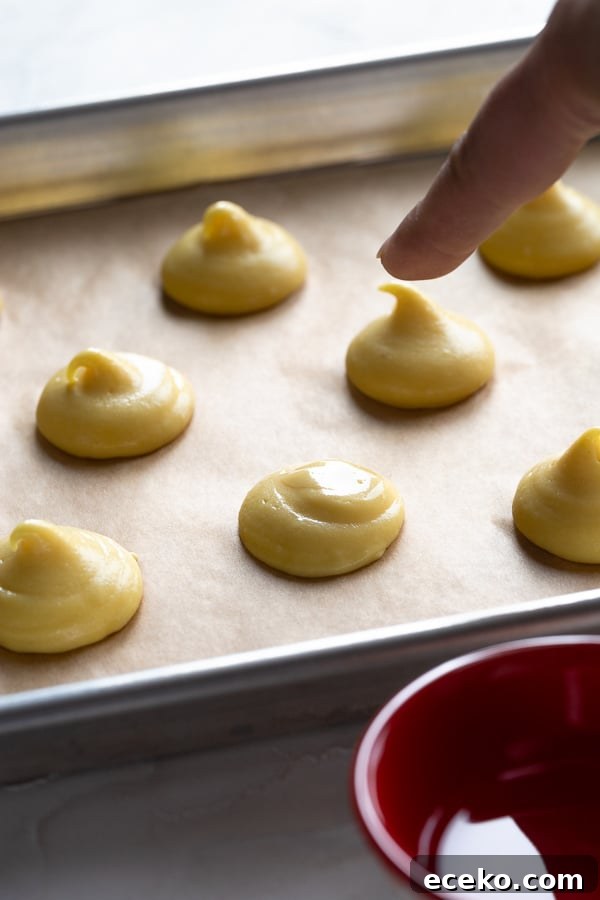 Raspberry Crème Puffs with Vanilla Cream Filling 6 Piped choux rounds on a baking sheet.