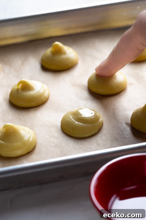 Raspberry Crème Puffs with Vanilla Cream Filling 7 Puffed choux shells cooling on a rack.