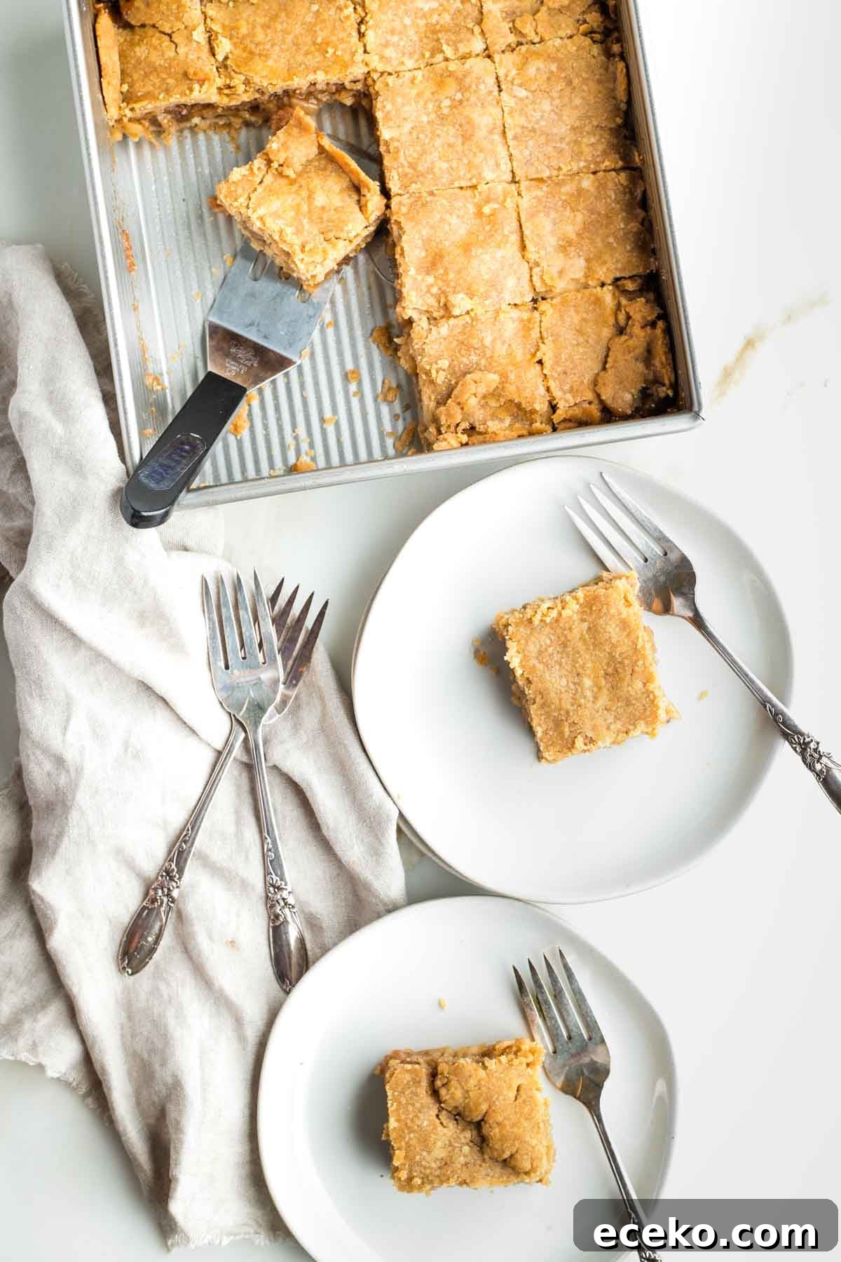 Vegan Apple Pie Bars with Cinnamon Streusel 2 Apple pie bars on plates with forks and in the square brownie pan being served.