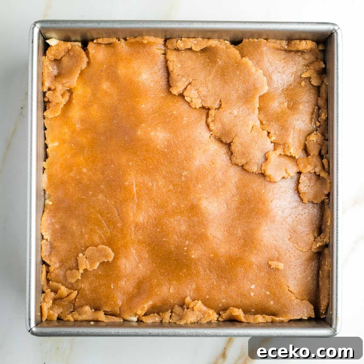 Vegan Apple Pie Bars with Cinnamon Streusel 19 Pie dough pieced together, covering apples in a square pan.