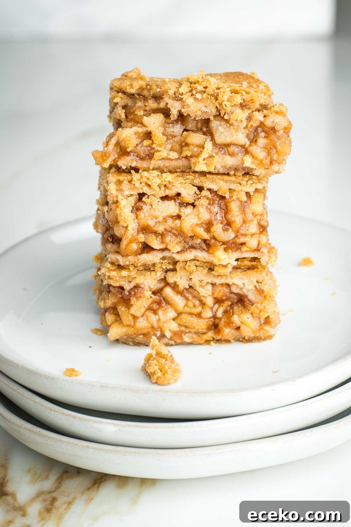 Vegan Apple Pie Bars with Cinnamon Streusel 23 Three apple pie bars stacked on top of each other, showing the filling inside.