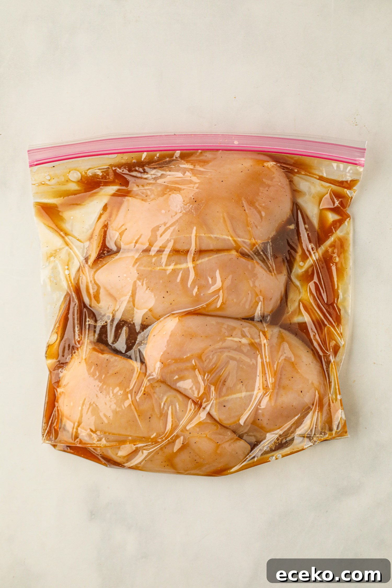 Sweet and Smoky Grilled Pineapple Chicken Recipe 4 Raw chicken breasts marinating in a resealable plastic bag