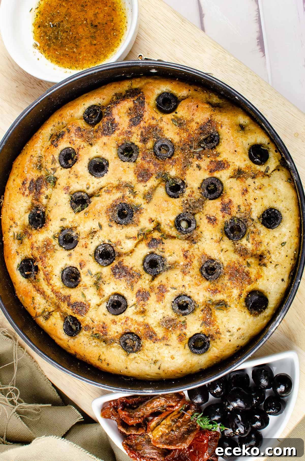 Olive and Herb Focaccia Bread Recipe 2 Cooked focaccia bread in a bread tin on a wooden chopping
