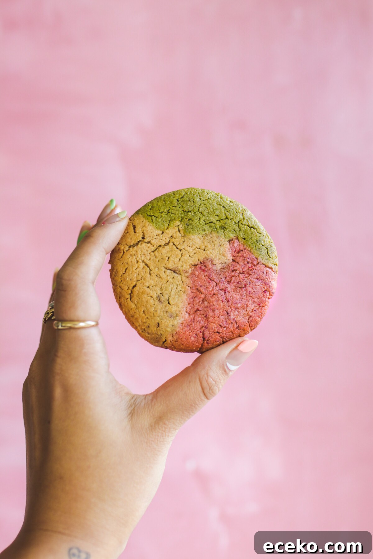 Gluten-Free Strawberry Matcha Sugar Cookie Recipe 3 a hand holding a gluten free sugar cookie in front of a pink background