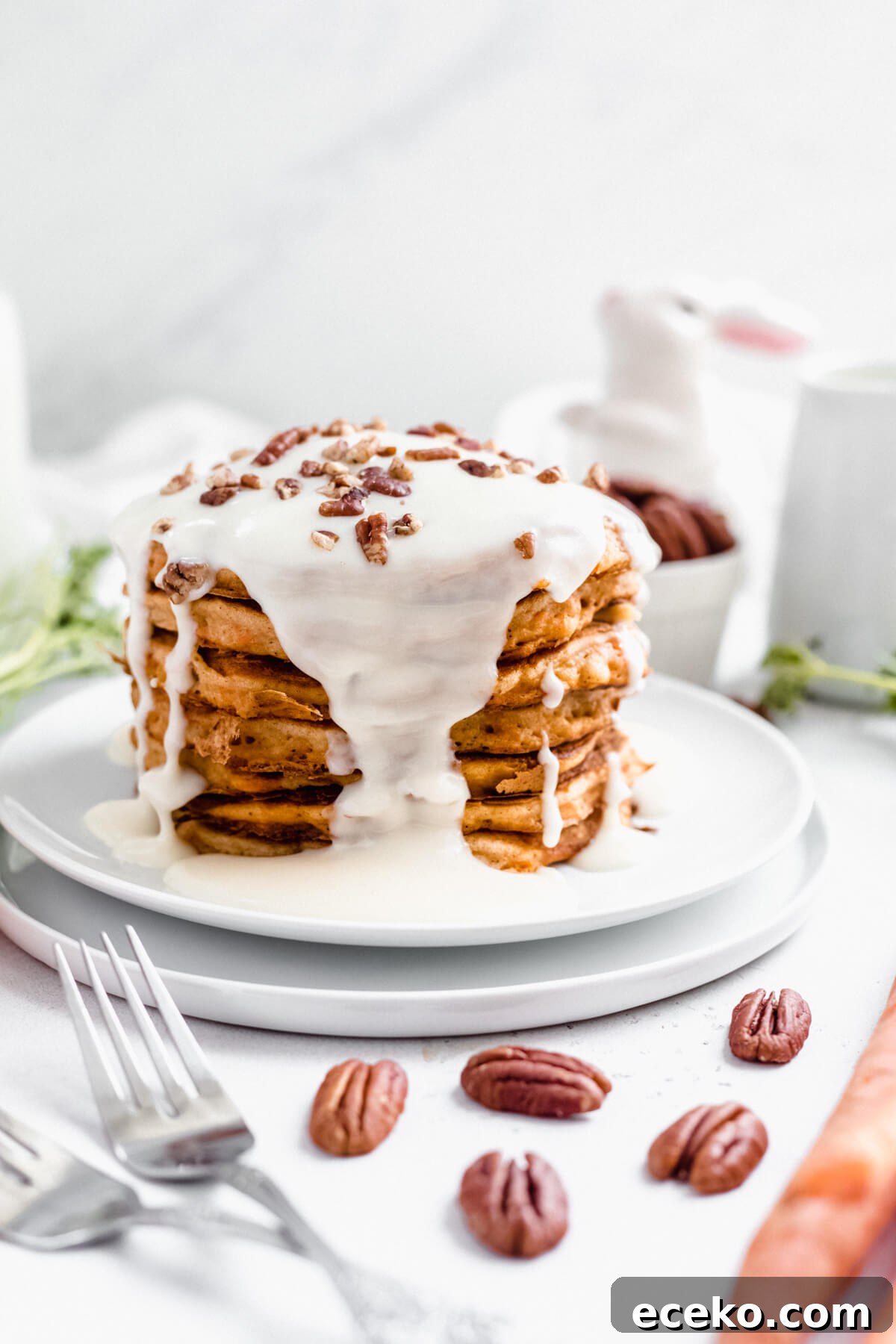 Carrot Cake Pancake Recipe with Cream Cheese Glaze 6 stack of pancakes on two white plates with two forks and pecans in front